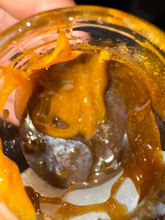 Rosin CBD Banana Kush montrant la consistance et la couleur du produit dans un pot en verre.